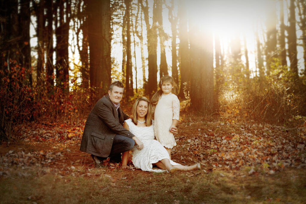 family posing for family portraits with golden hour light behind them 