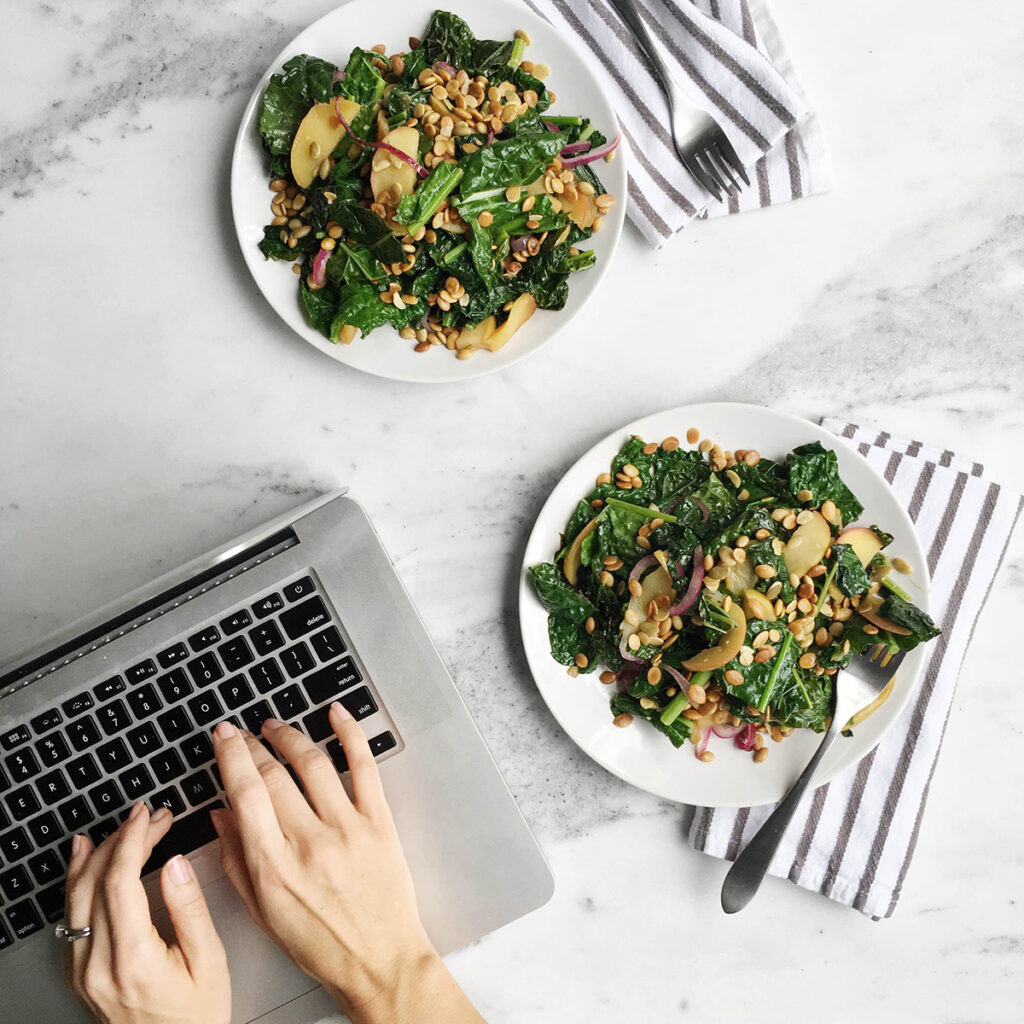 healthy salad next to a woman on a laptop as a meal idea for work-life balance as a photographer