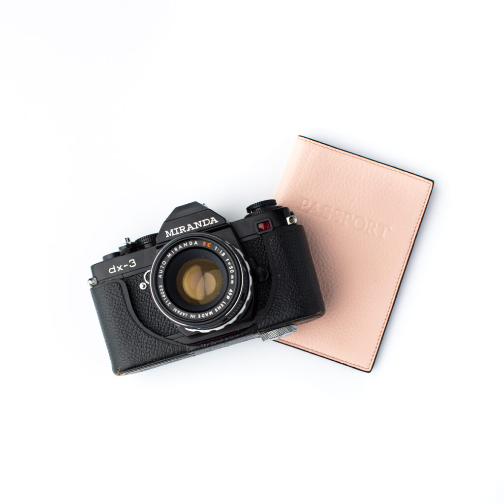 camera sitting on a desktop with a passport encouraging work-life balance as a photographer