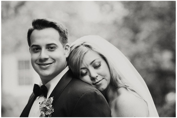 wedding couple in black and white - bride resting head on grooms shoulder