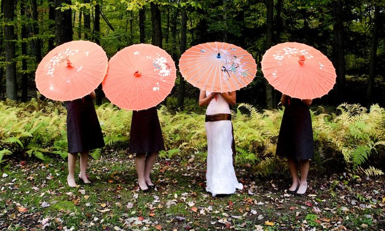 bride with bridesmaids behind umbrellas taking a moment to be intentional behind the camera